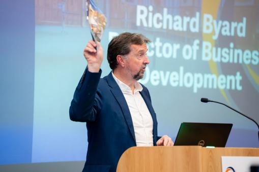 Image of Richard Byard, Director of Business Development at OxLEP holding up document on stage at Marketplace Event