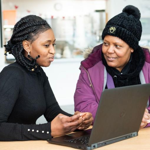 Image of individual seeking employability support, sat looking at laptop with other individual offering guidance